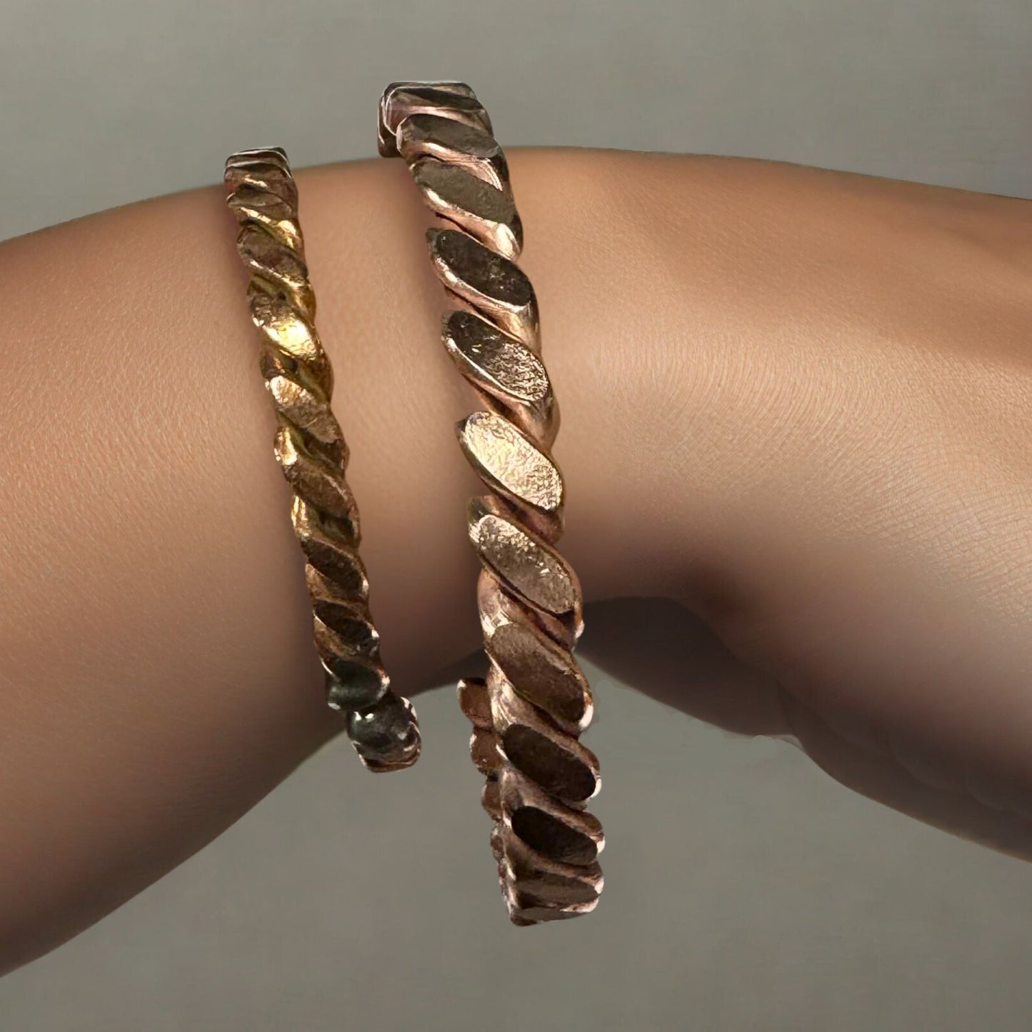 Two copper bracelets for healing on a wrist against a neutral background