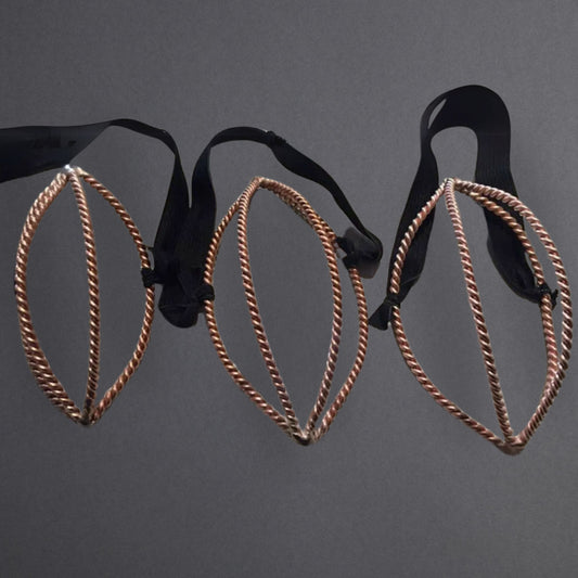 Pair of black and copper nose mask tensor rings on a dark gray background