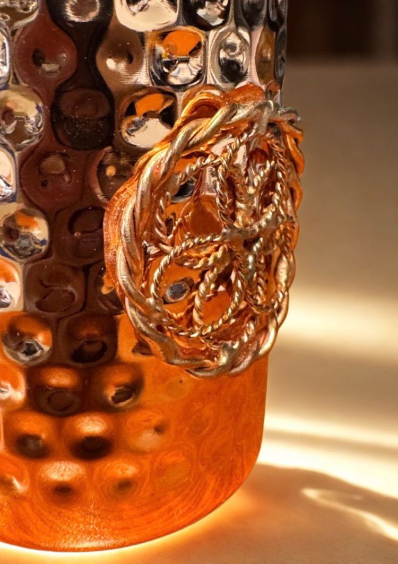 Close-up of a tensor ring with intricate design on copper mug on a textured surface