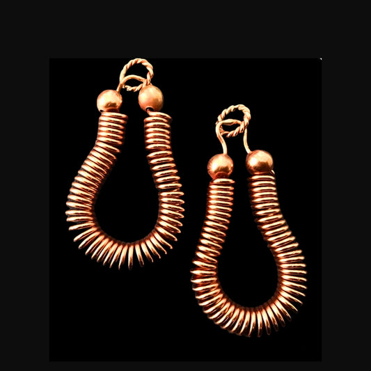 Pair of copper coil pendants on a black background