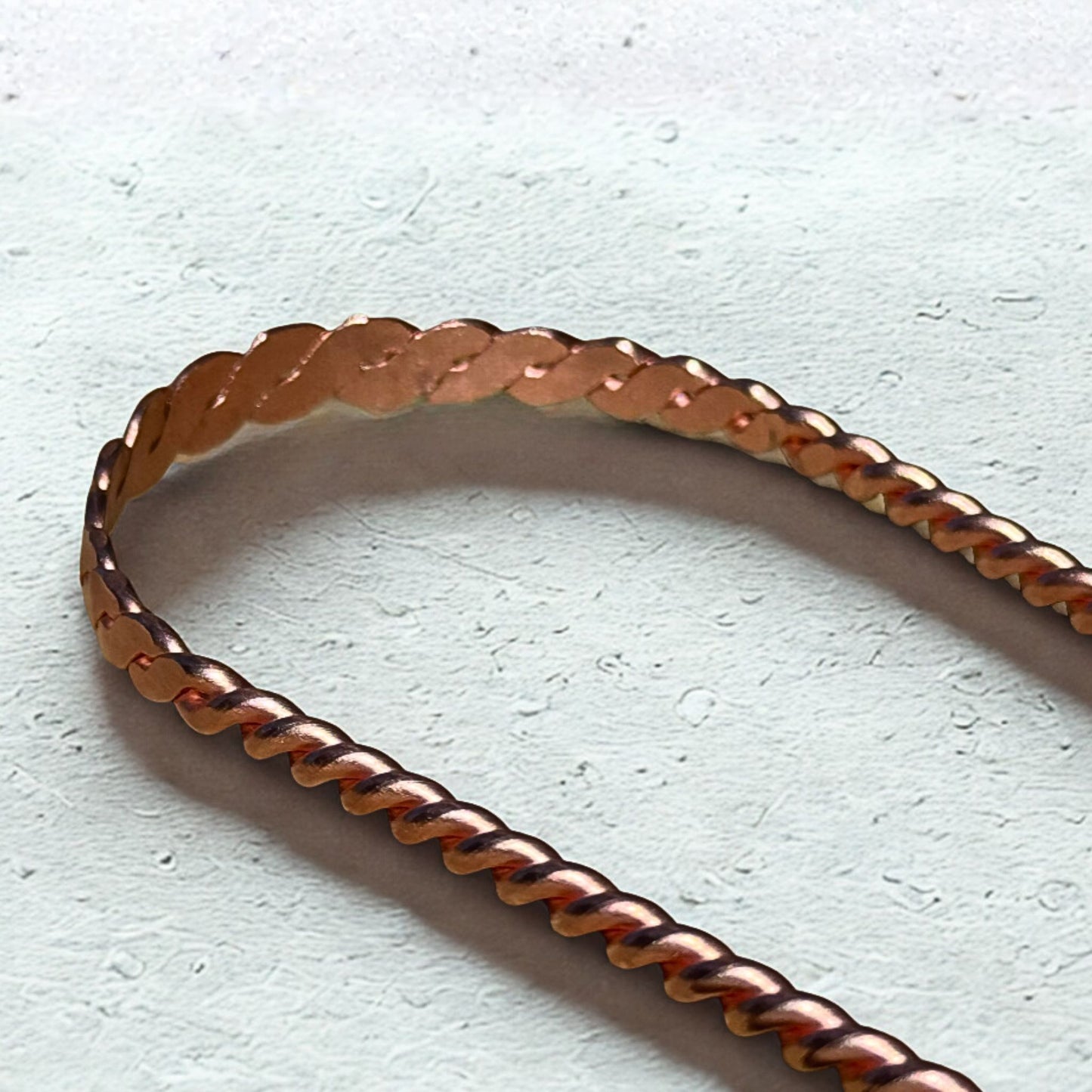 Copper tongue scraper on a light gray background