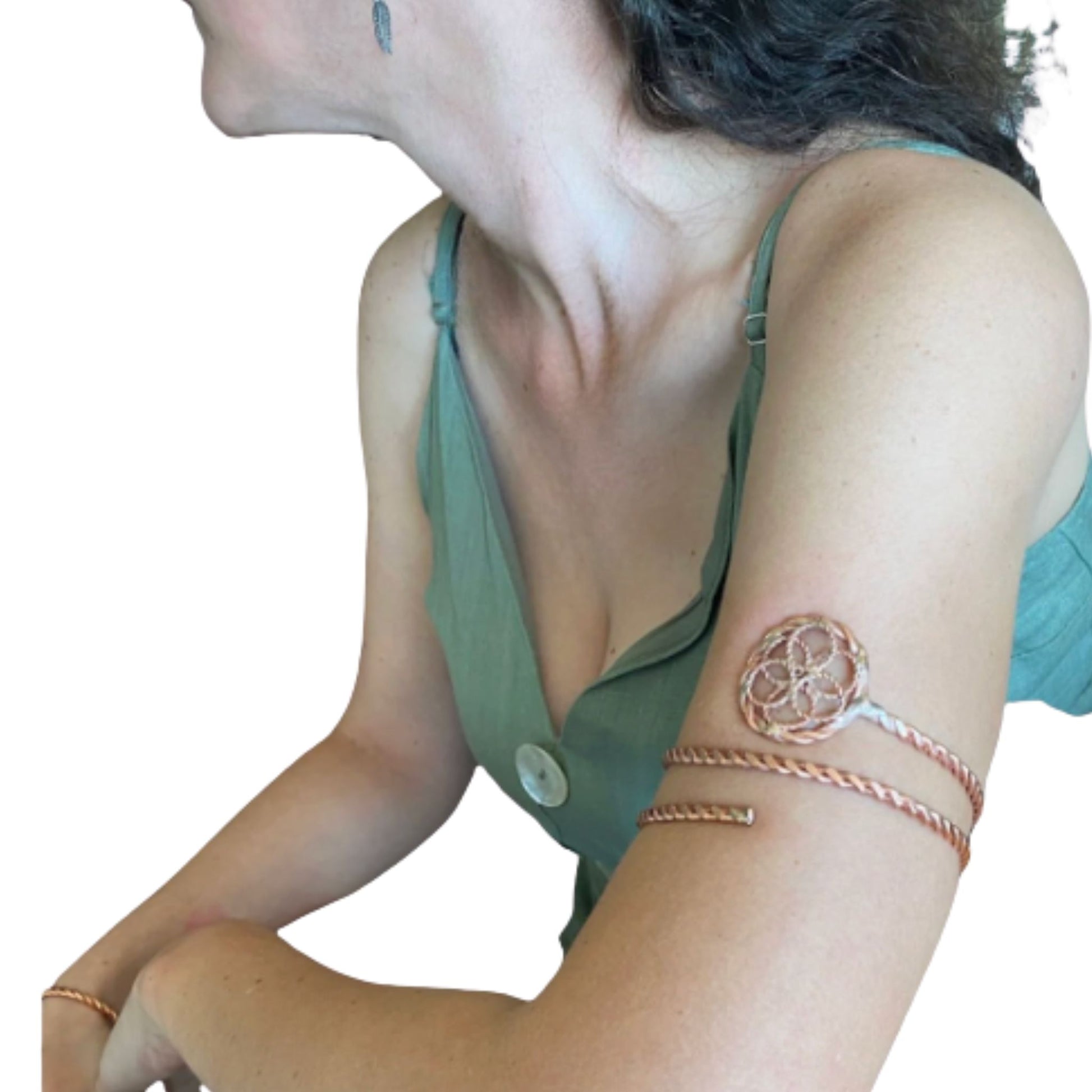 Woman wearing a green top with a button and a copper arm wrap bracelet on a white background