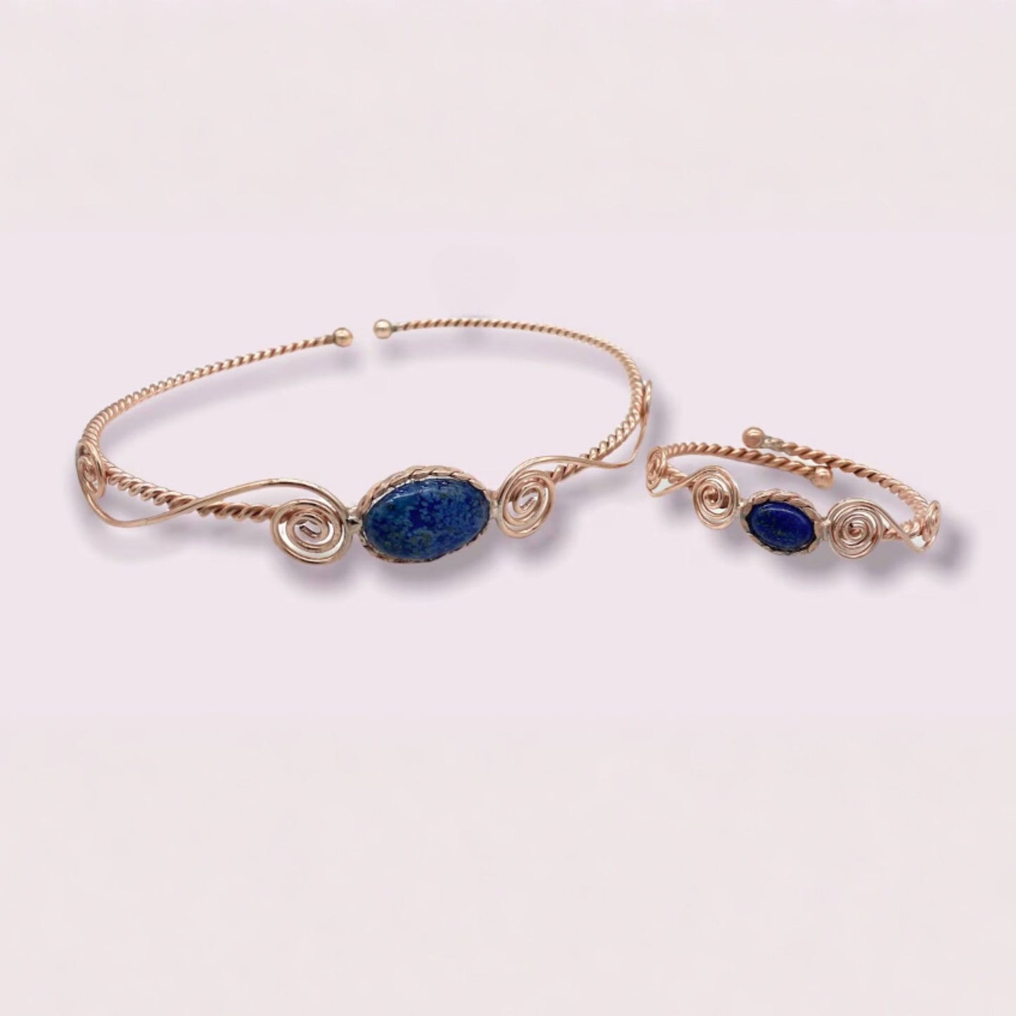 copper head and arm band with blue stones on a light pink background