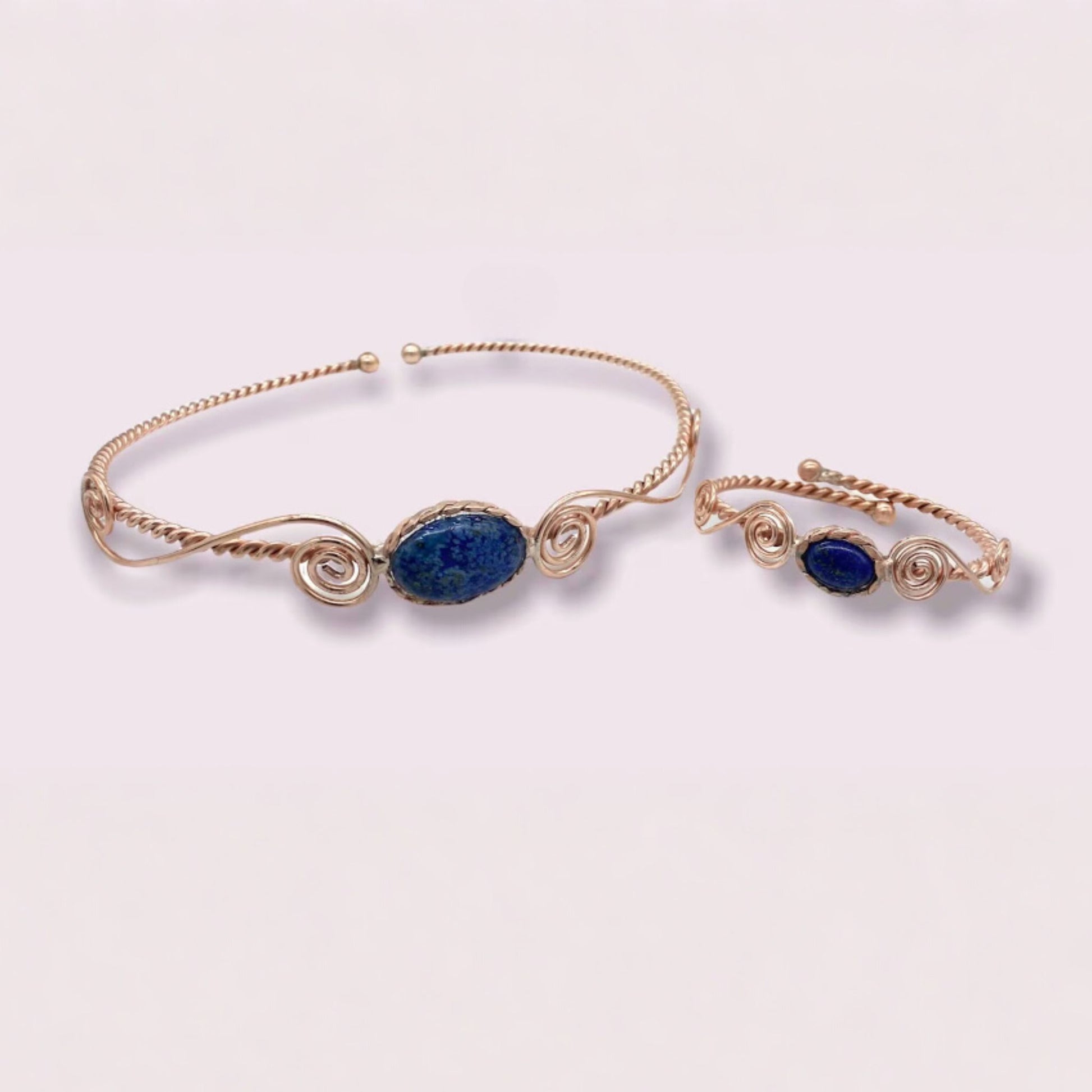 copper head and arm band with blue stones on a light pink background