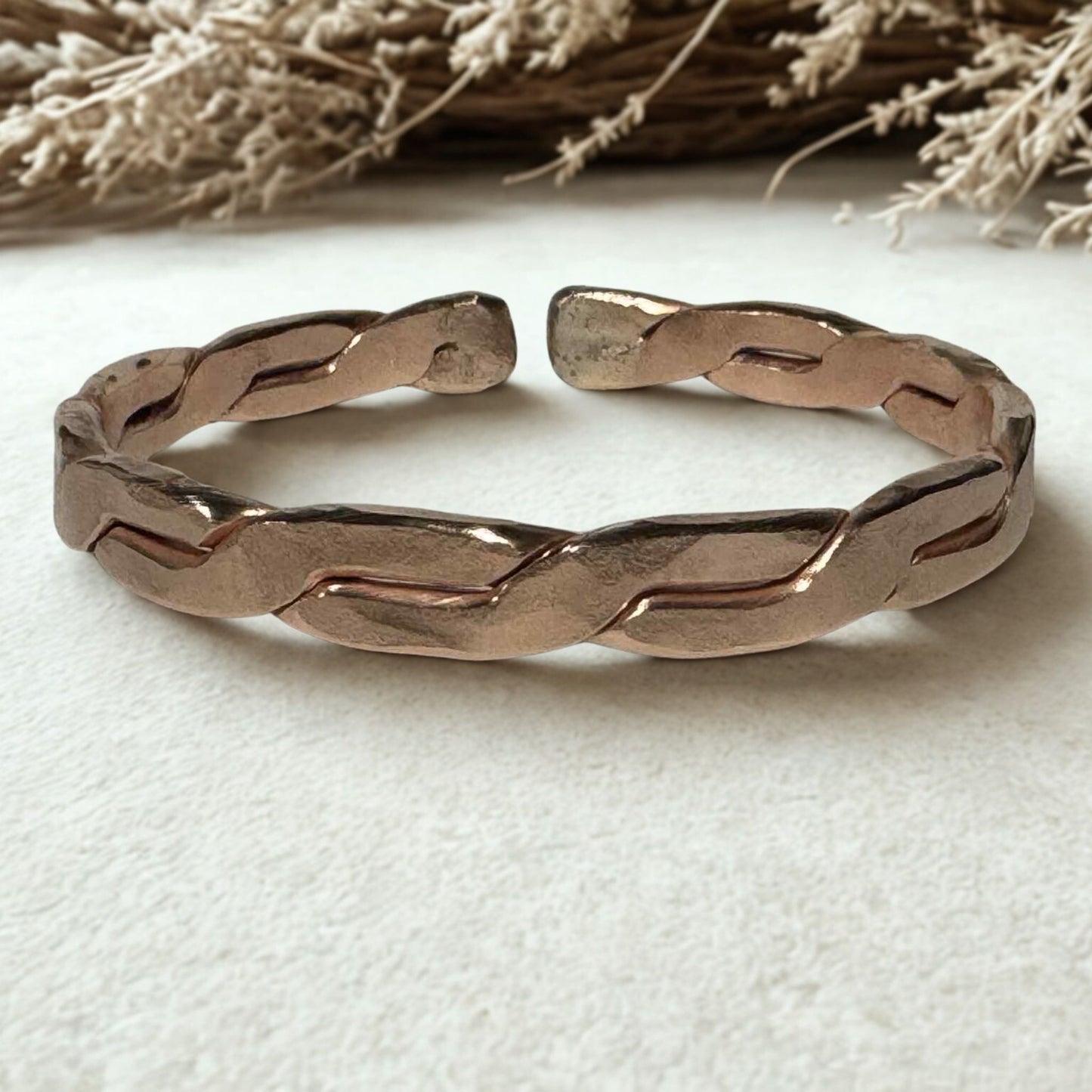 Bronze braided bracelet on a white fabric background Copper EMF Protection