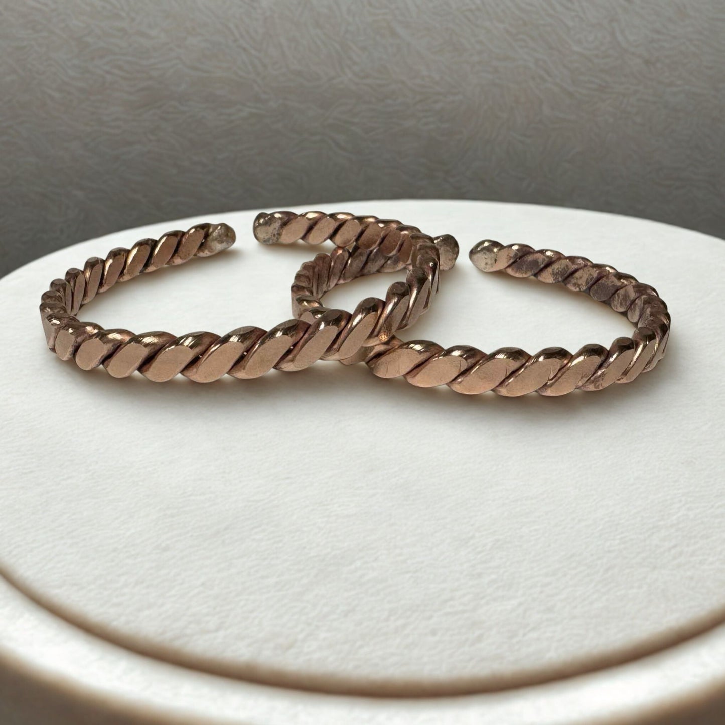 copper hoop earrings on a white surface with a gray background