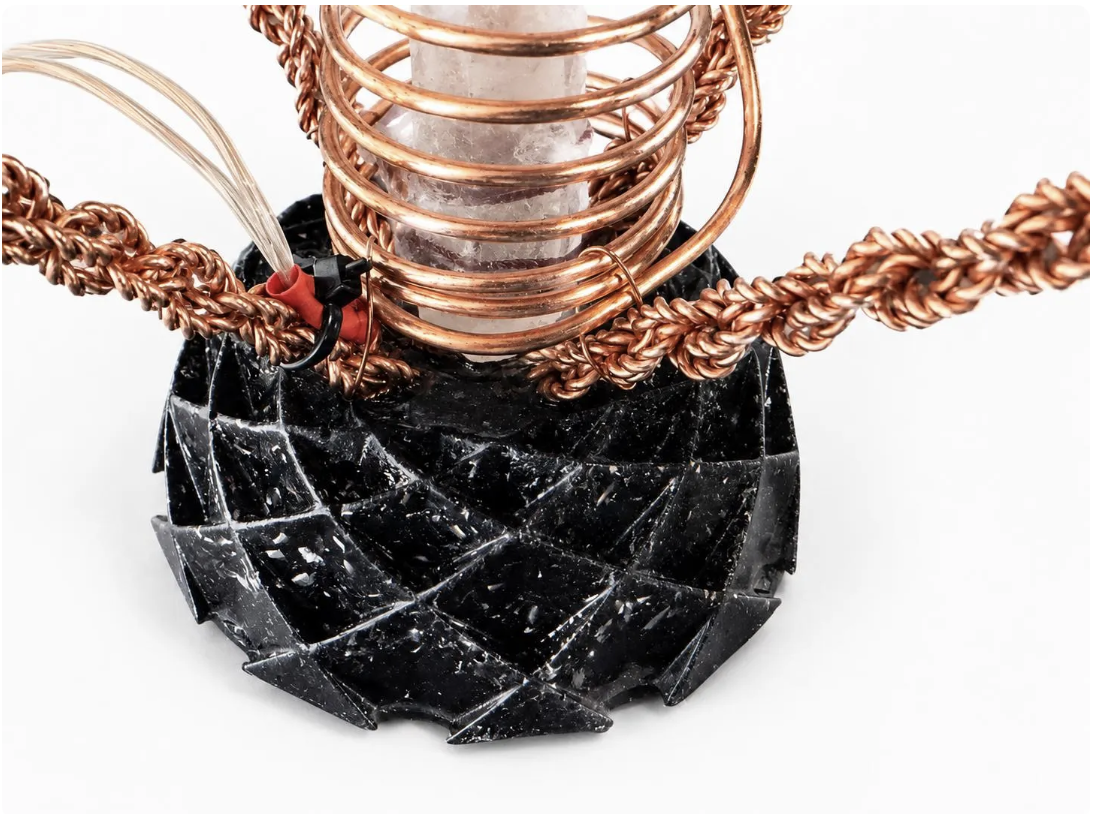 close up of base black stone and copper tensor wiring on a white background