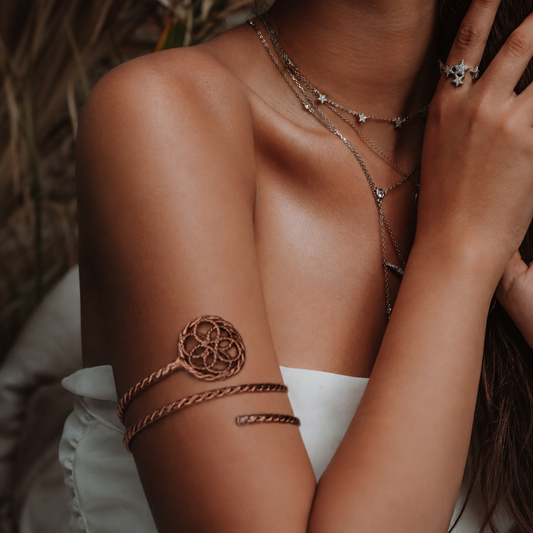 Close-up of a person wearing multiple pieces of silver jewelry on skin and clothing.