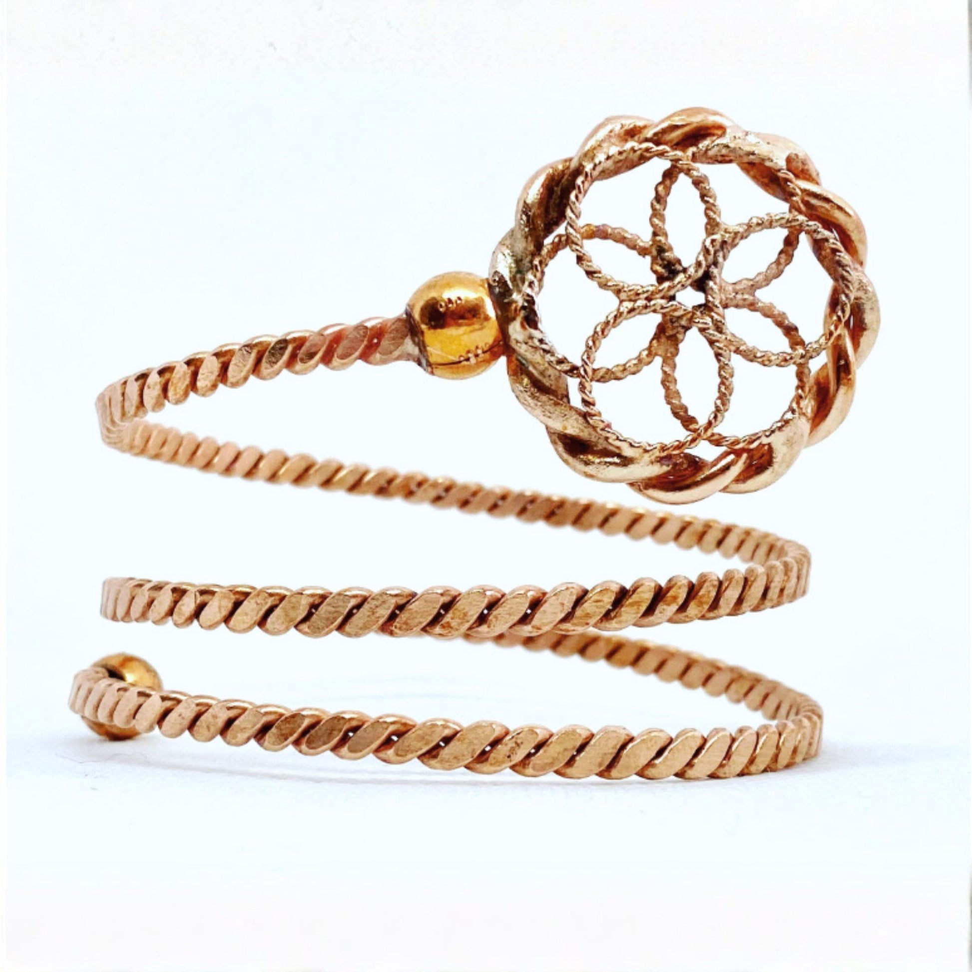 Copper spiral ring with intricate design on a white background