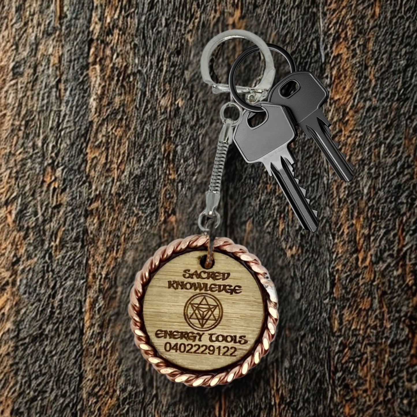 Wooden keychain with engraved text and symbols on a wooden surface copper EMF 
