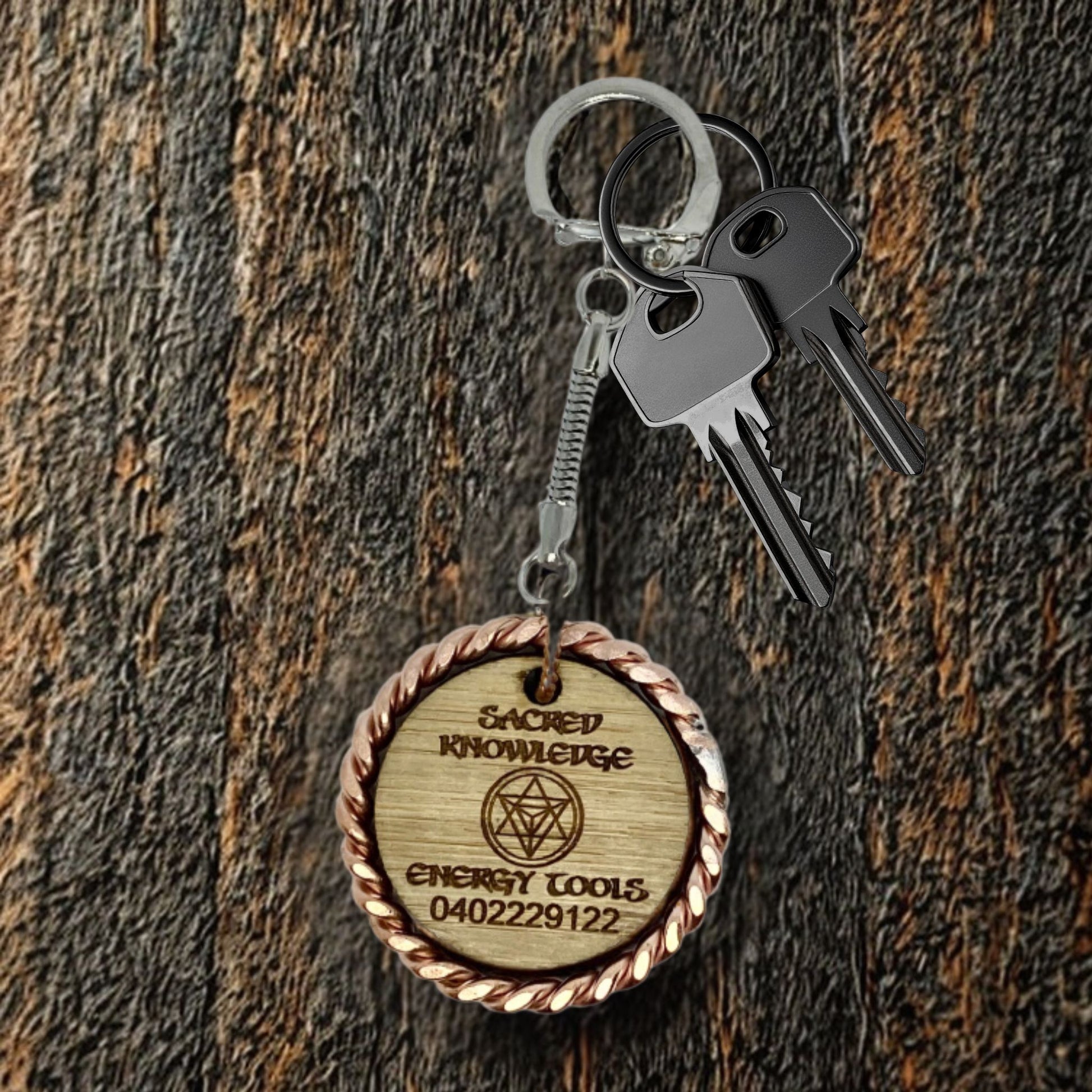 Wooden keychain with engraved text and symbols on a wooden surface copper EMF 