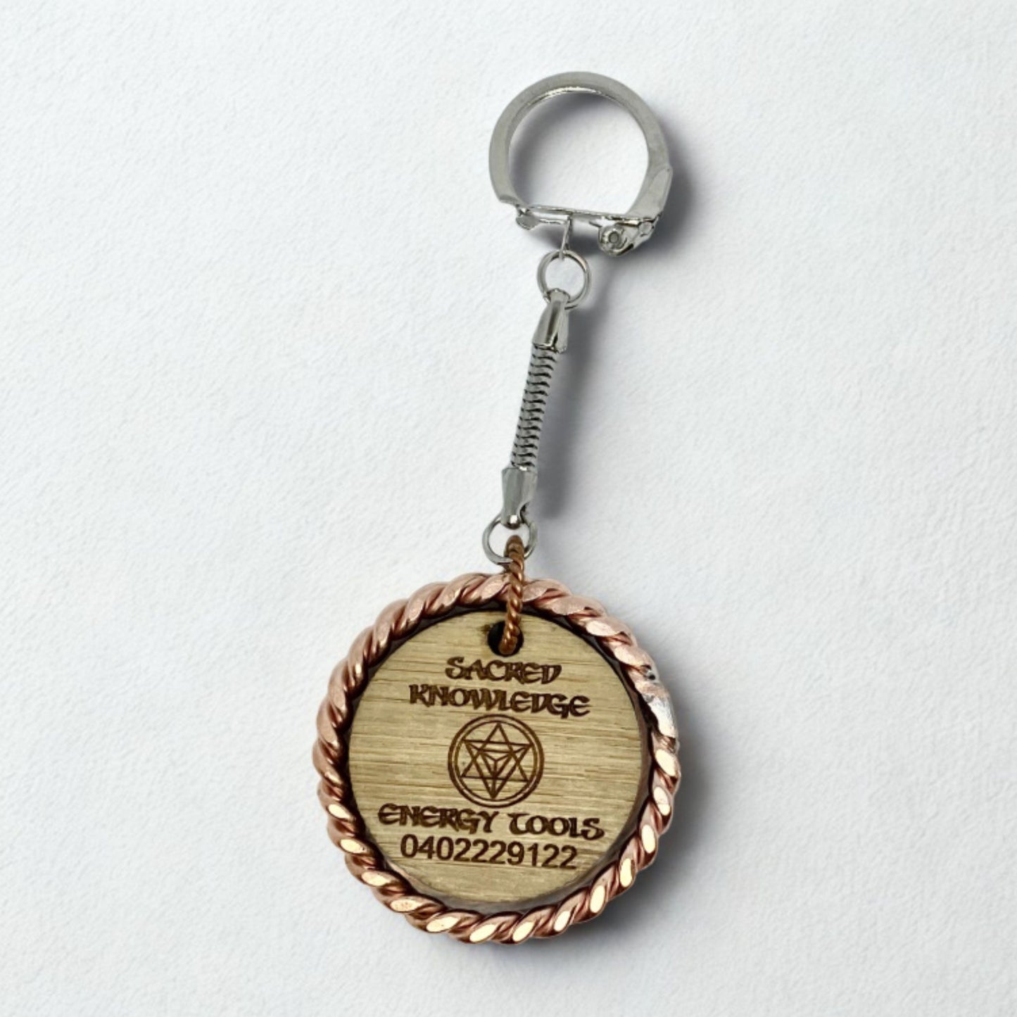 copper EMF Wooden keychain with circular design and text on a white background