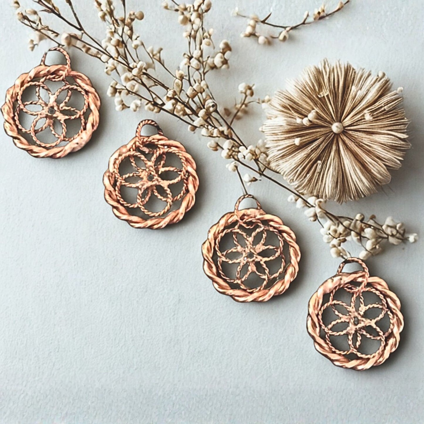 Copper lotus pendants on a light blue background with decorative branches.