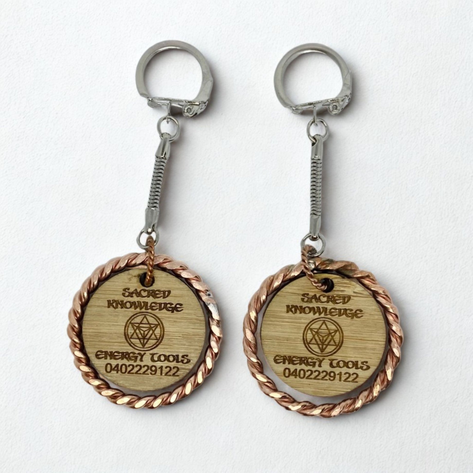 Two wooden keychains with metal loops on a white background copper EMF 