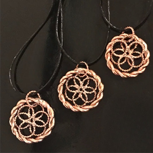 Three copper-colored circular pendants on black cords against a black background