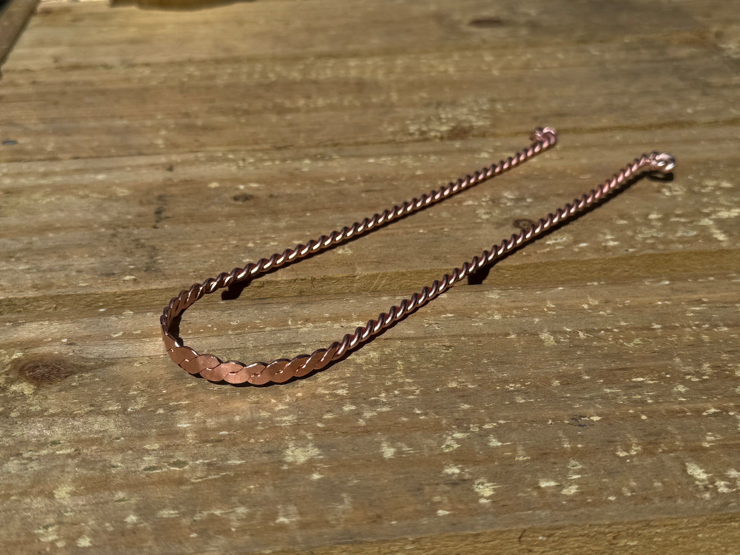 Copper  tongue scraper on a wooden surface