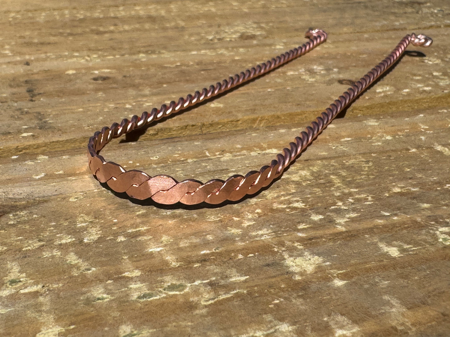 Copper  tongue scraper  on a wooden surface
