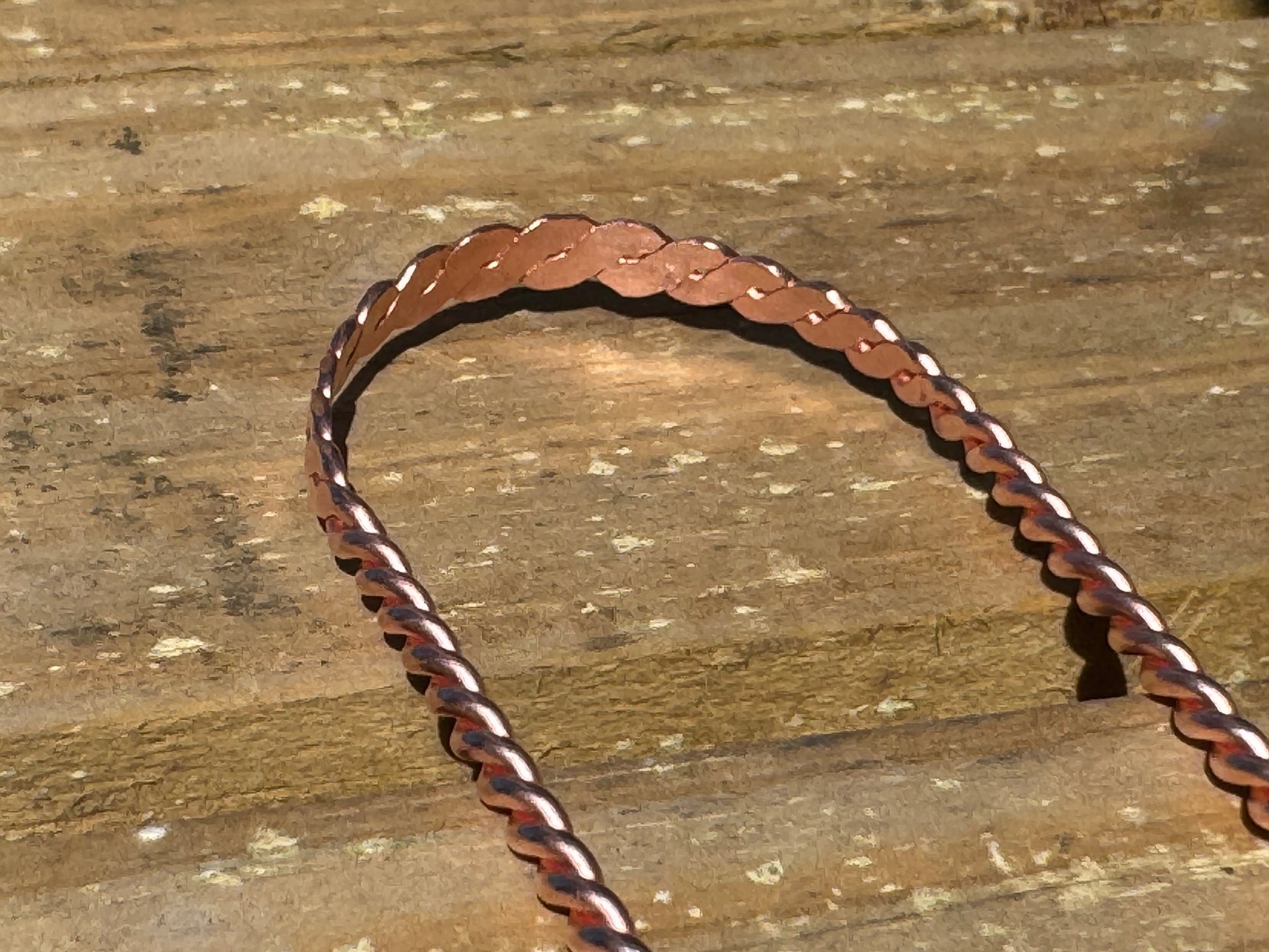 Copper  tongue scraper  on a wooden surface