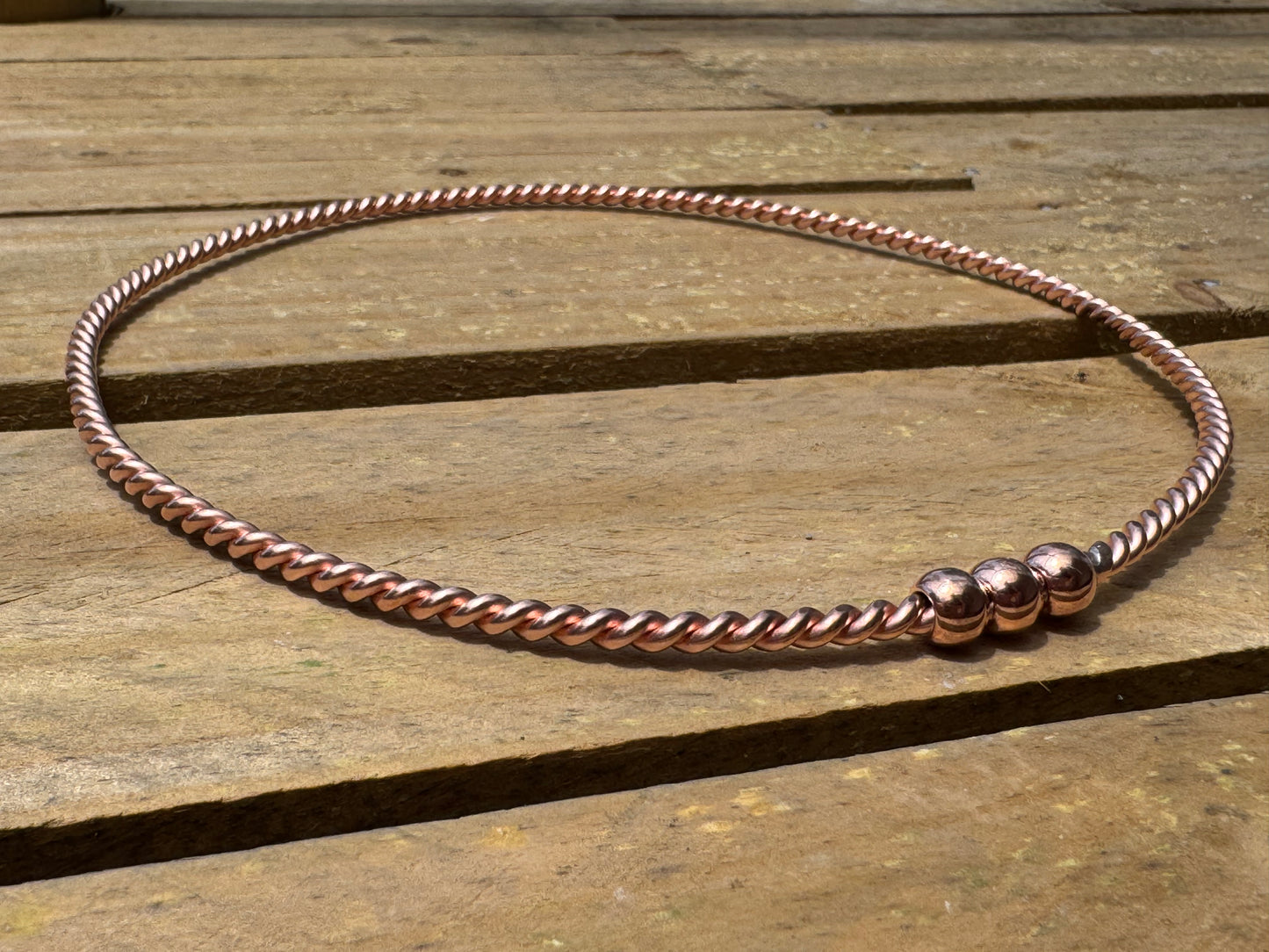 Copper beaded ring on a wooden surface