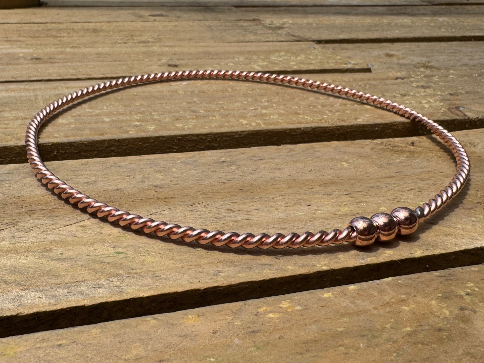 Copper beaded ring on a wooden surface