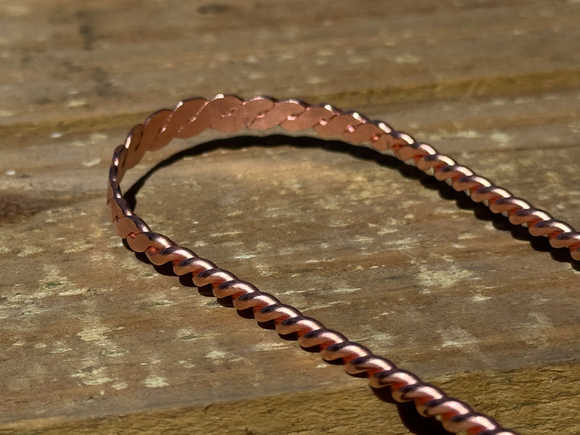 Copper  tongue scraper chain on a wooden surface